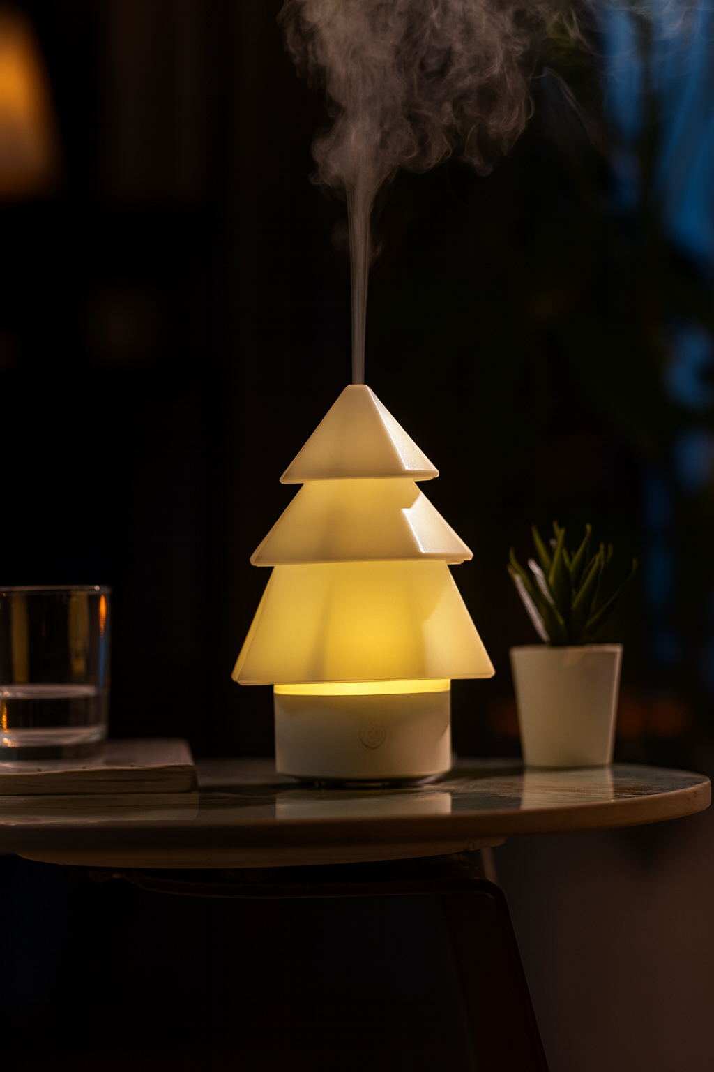 Warm glowing Christmas tree-shaped aroma diffuser releasing gentle mist on a glass table in a softly lit evening room, ThuisGemak.