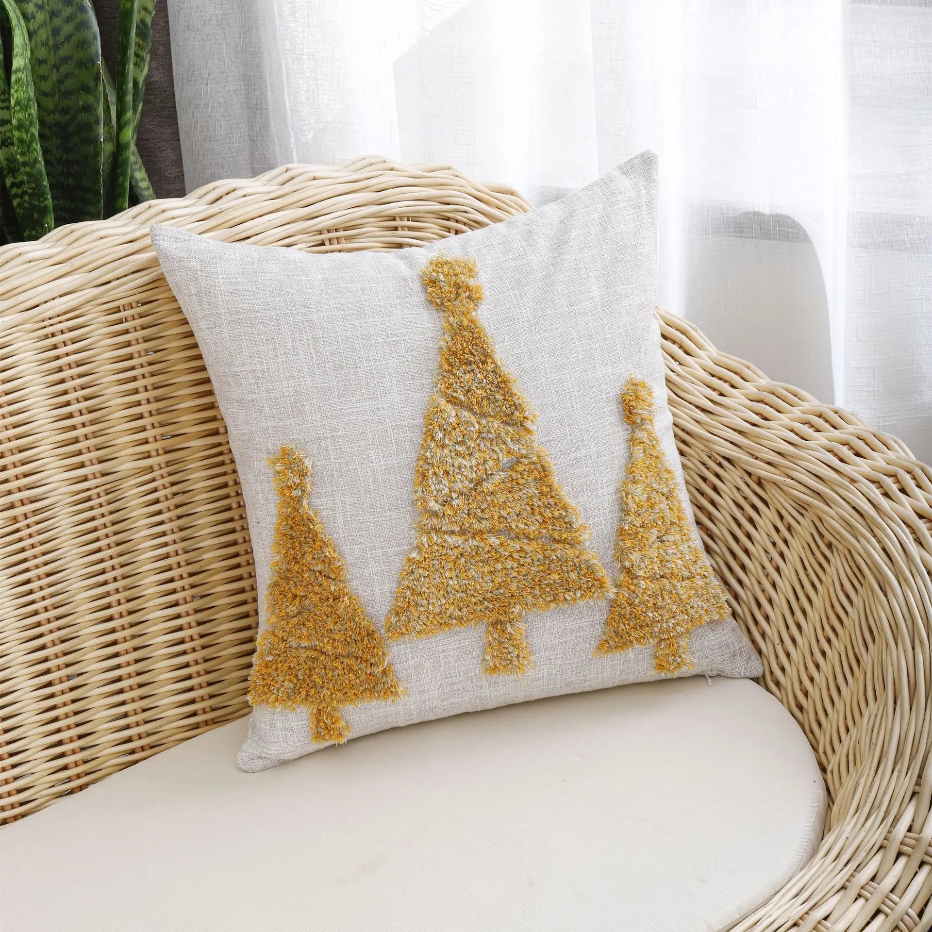 Thuisgemak Festive Tree Cushion with gold tufted Christmas tree design on a rattan sofa in a bright UK living room, radiating warmth and festive elegance.