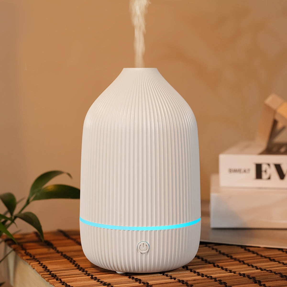 Elegant ribbed ceramic aroma diffuser with blue light base releasing fine mist on a bamboo surface in a calm living room, ThuisGemak.