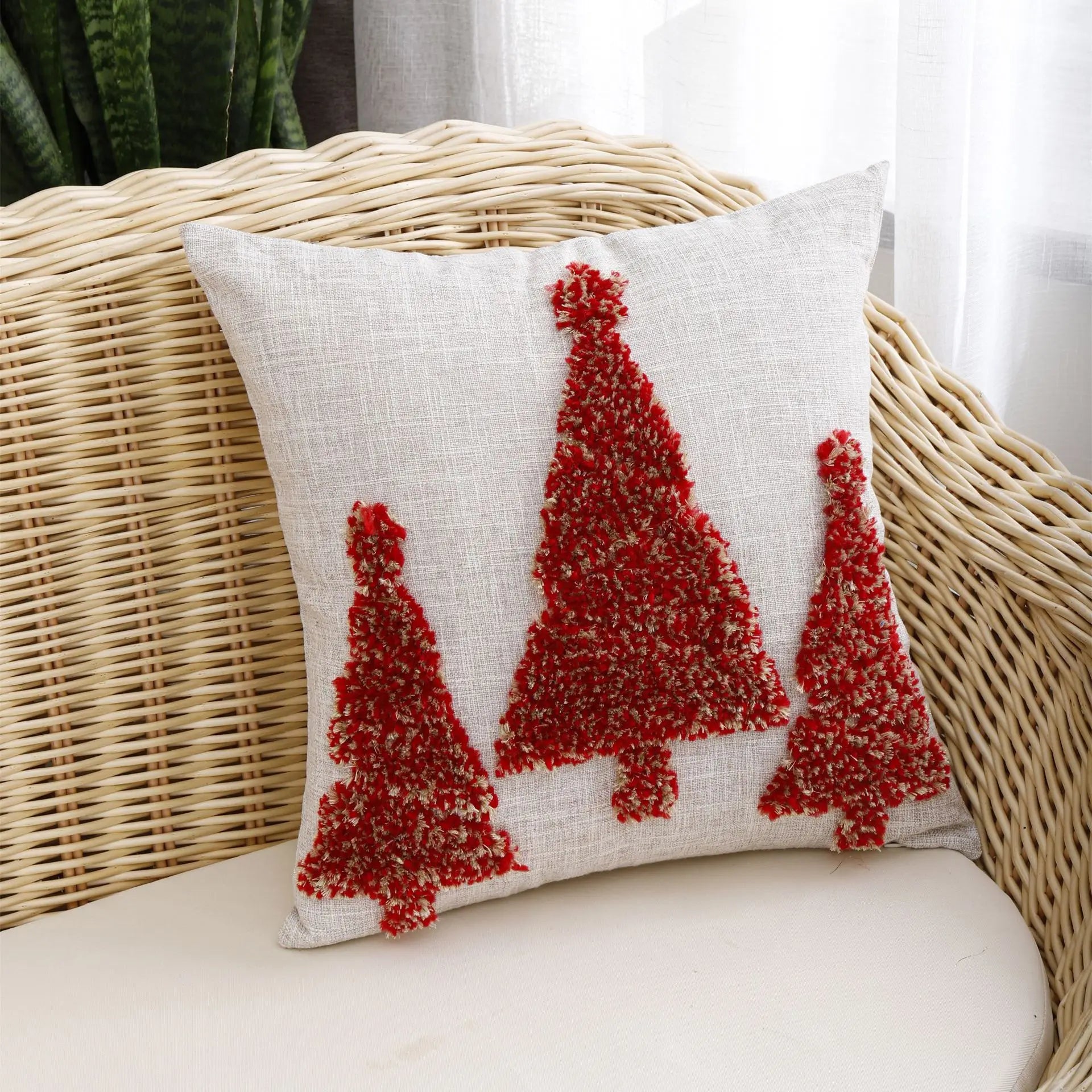 Thuisgemak Festive Tree Cushion with red tufted Christmas tree design on a rattan sofa in a bright UK living room, adding warmth and seasonal charm.